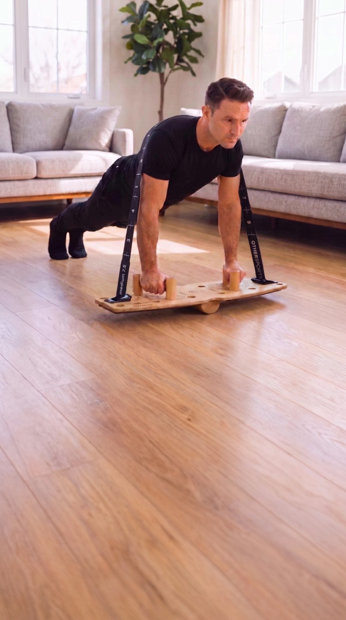 Mann macht Liegestütze auf dem Push up Board mit Band und Halbrolle