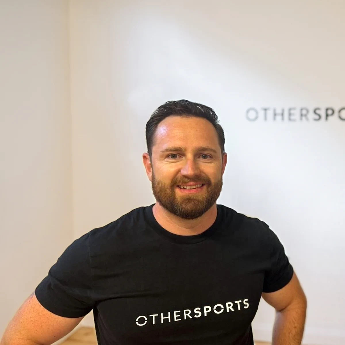 Christian Warth im Trainingsraum, im Hintergrund das OTHERSPORTS-Schild